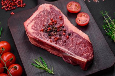 Taze taze taze taze New York bifteği, tuz, baharat ve çimento arka planda otlar.