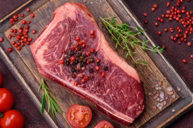 Taze taze taze taze New York bifteği, tuz, baharat ve çimento arka planda otlar.