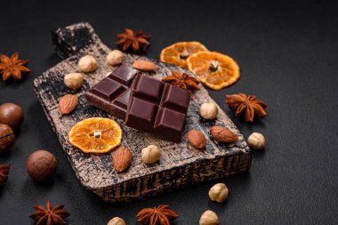 Koyu beton bir zeminde tahta bir kesme tahtasının üzerinde lezzetli siyah çikolata parçalanmış.