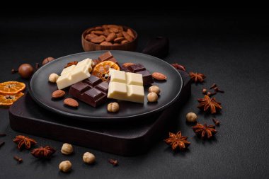 Koyu beton bir arka planda siyah bir tabakta parçalanmış çeşitli lezzetli çikolataların karışımı.