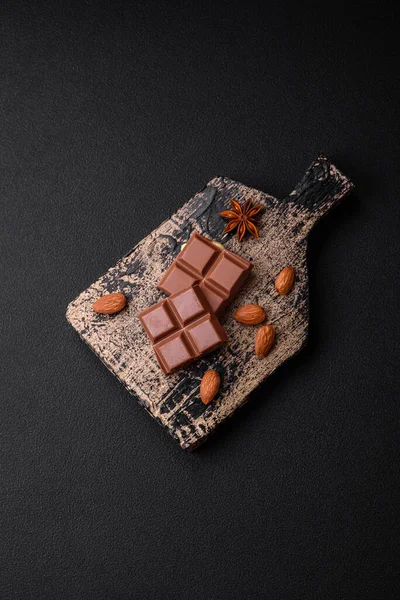 濃いコンクリートの背景に木製のまな板の上にキューブに分割おいしい甘いミルクチョコレート — ストック写真