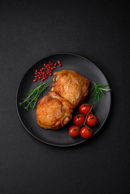 Tuz, baharat ve otlarla pişirilmiş lezzetli sulu tavuk butları koyu beton arka planda seramik bir tabakta.