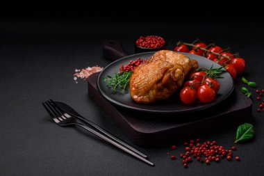 Tuz, baharat ve otlarla pişirilmiş lezzetli sulu tavuk butları koyu beton arka planda seramik bir tabakta.