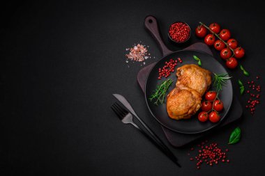 Tuz, baharat ve otlarla pişirilmiş lezzetli sulu tavuk butları koyu beton arka planda seramik bir tabakta.