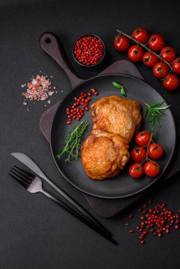 Tuz, baharat ve otlarla pişirilmiş lezzetli sulu tavuk butları koyu beton arka planda seramik bir tabakta.