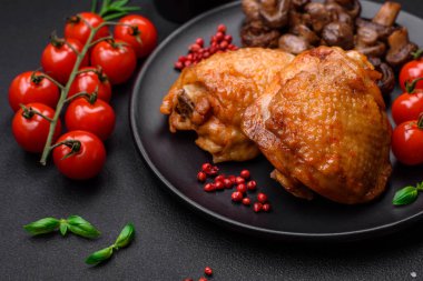 Tuz, baharat ve otlarla pişirilmiş lezzetli sulu tavuk butları koyu beton arka planda seramik bir tabakta.