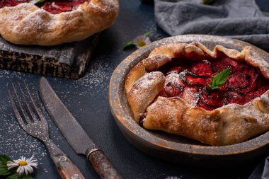 Koyu dokulu arka planda yabani çiçeklerle ev yapımı lezzetli, ev yapımı, kır çileği turtası.