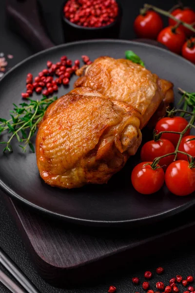 stock image Delicious juicy chicken thighs baked with salt, spices and herbs in a ceramic plate on a dark concrete background