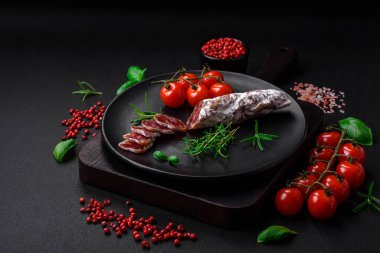 Taze füme sosis, tuz, baharat ve otlarla birlikte koyu beton bir arka planda.