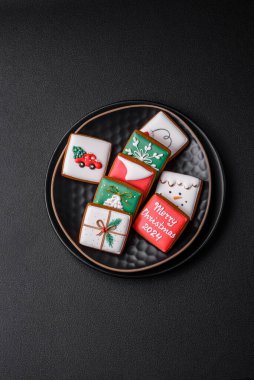 Lezzetli taze Noel zencefilli ekmeği, koyu beton arka planda seramik bir tabakta şenlikli süsler.