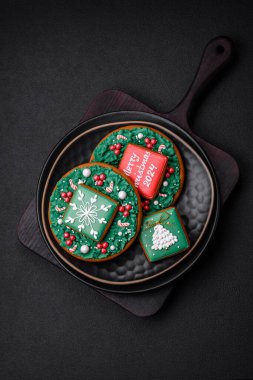 Lezzetli taze Noel zencefilli ekmeği, koyu beton arka planda seramik bir tabakta şenlikli süsler.