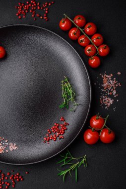 Koyu beton zeminde domates, tuz, baharat ve otlar pişirmek için gerekli malzemeler.