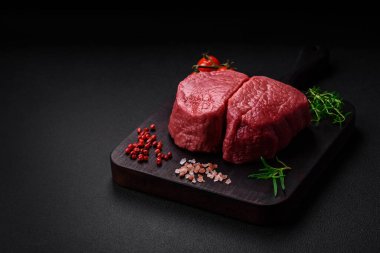 Tuz, baharat ve otlarla çevrili çiğ biftek, dokulu bir arka planda ızgara için hazırlandı.