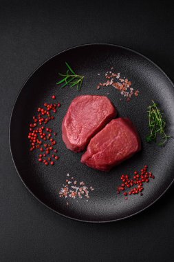 Tuz, baharat ve otlarla çevrili çiğ biftek, dokulu bir arka planda ızgara için hazırlandı.