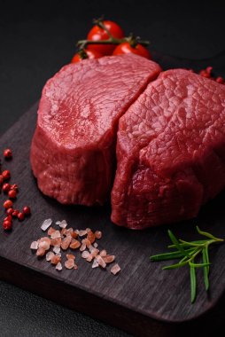 Tuz, baharat ve otlarla çevrili çiğ biftek, dokulu bir arka planda ızgara için hazırlandı.