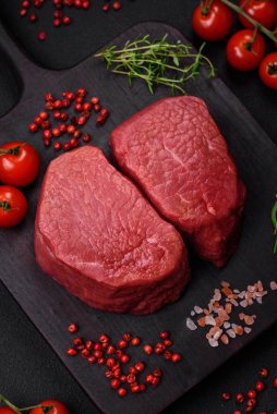 Tuz, baharat ve otlarla çevrili çiğ biftek, dokulu bir arka planda ızgara için hazırlandı.