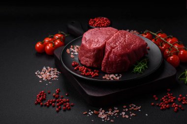 Tuz, baharat ve otlarla çevrili çiğ biftek, dokulu bir arka planda ızgara için hazırlandı.