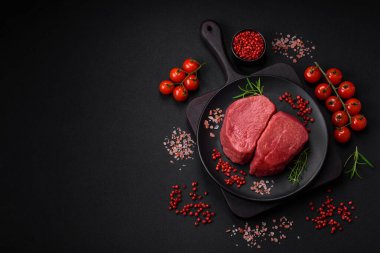 Tuz, baharat ve otlarla çevrili çiğ biftek, dokulu bir arka planda ızgara için hazırlandı.