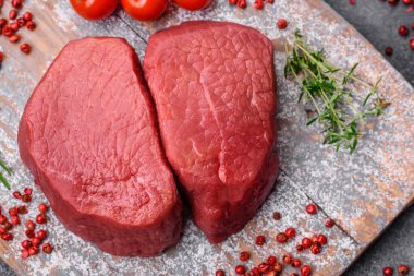 Tuz, baharat ve otlarla çevrili çiğ biftek, dokulu bir arka planda ızgara için hazırlandı.