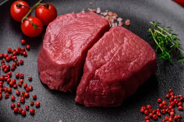 Tuz, baharat ve otlarla çevrili çiğ biftek, dokulu bir arka planda ızgara için hazırlandı.