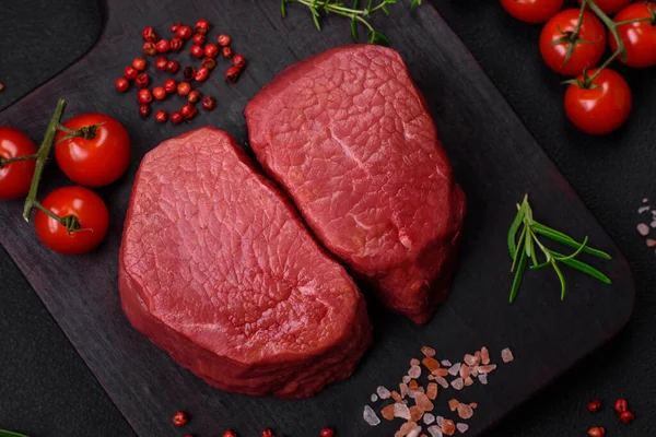 Tuz, baharat ve otlarla çevrili çiğ biftek, dokulu bir arka planda ızgara için hazırlandı.