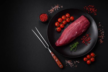 Koyu beton arka planda baharatlı, tuzlu ve otlu sulu çiğ biftek. Et yemeği pişirmeye hazırlanıyor.