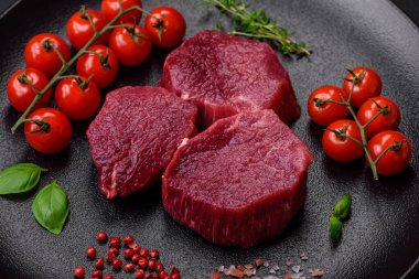 Koyu beton arka planda baharatlı, tuzlu ve otlu sulu çiğ biftek. Et yemeği pişirmeye hazırlanıyor.