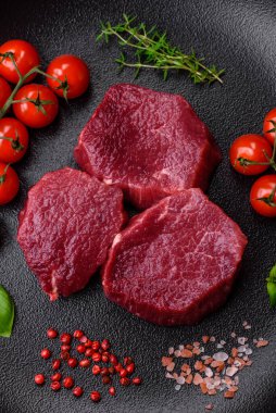 Koyu beton arka planda baharatlı, tuzlu ve otlu sulu çiğ biftek. Et yemeği pişirmeye hazırlanıyor.