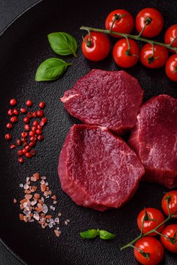 Koyu beton arka planda baharatlı, tuzlu ve otlu sulu çiğ biftek. Et yemeği pişirmeye hazırlanıyor.