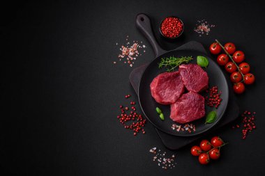 Koyu beton arka planda baharatlı, tuzlu ve otlu sulu çiğ biftek. Et yemeği pişirmeye hazırlanıyor.