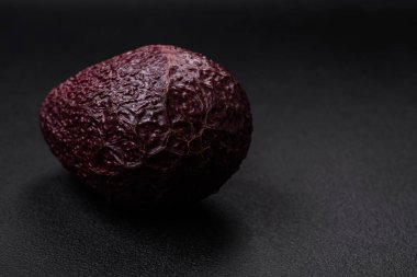 Taze, olgun, koyu beton arka planda yumuşak kahverengi avokado. Sağlıklı yemek malzemeleri.