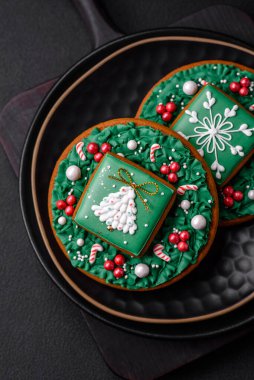 Güzel Noel ya da yeni yıl renkli ev yapımı zencefilli kurabiyeler seramik tabakta koyu beton arka planda