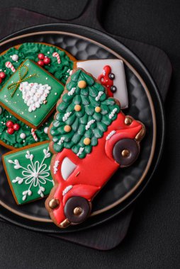 Güzel Noel ya da yeni yıl renkli ev yapımı zencefilli kurabiyeler seramik tabakta koyu beton arka planda