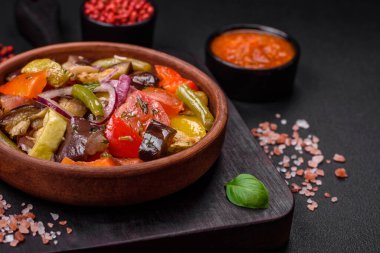 Domatesli taze vejetaryen salatası, yeşil fasulye, patlıcan, biber, tuz, baharat ve otlar koyu beton arka planda.