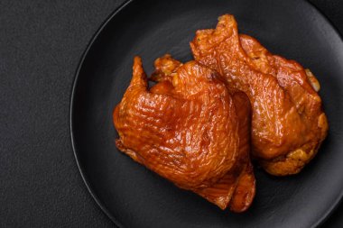 Lezzetli kızarmış ya da tütsülenmiş tavuk butları. Koyu beton bir arka planda baharat ve otlarla ızgara.