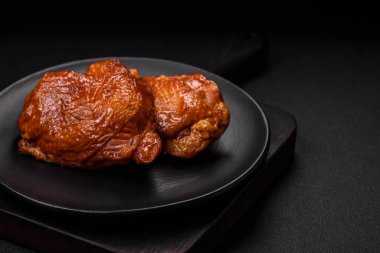 Lezzetli kızarmış ya da tütsülenmiş tavuk butları. Koyu beton bir arka planda baharat ve otlarla ızgara.