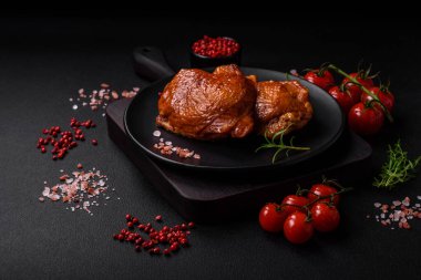 Lezzetli kızarmış ya da tütsülenmiş tavuk butları. Koyu beton bir arka planda baharat ve otlarla ızgara.