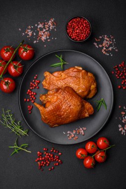 Lezzetli kızarmış ya da tütsülenmiş tavuk butları. Koyu beton bir arka planda baharat ve otlarla ızgara.