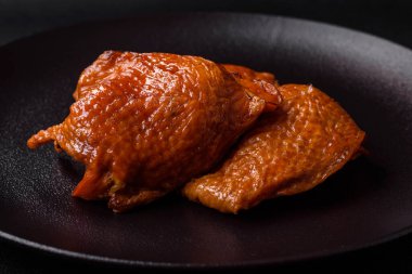 Lezzetli kızarmış ya da tütsülenmiş tavuk butları. Koyu beton bir arka planda baharat ve otlarla ızgara.