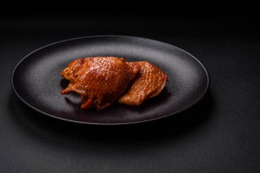 Lezzetli kızarmış ya da tütsülenmiş tavuk butları. Koyu beton bir arka planda baharat ve otlarla ızgara.