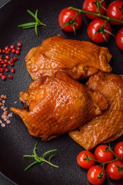 Lezzetli kızarmış ya da tütsülenmiş tavuk butları. Koyu beton bir arka planda baharat ve otlarla ızgara.