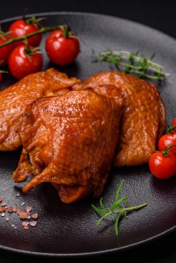 Lezzetli kızarmış ya da tütsülenmiş tavuk butları. Koyu beton bir arka planda baharat ve otlarla ızgara.