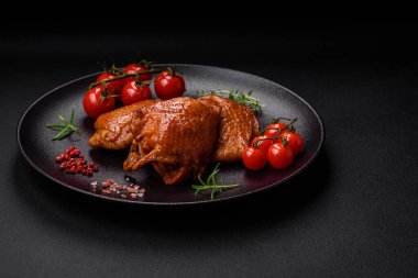 Lezzetli kızarmış ya da tütsülenmiş tavuk butları. Koyu beton bir arka planda baharat ve otlarla ızgara.