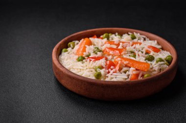 Lezzetli, sebzeli haşlanmış pirinç ya da koyu beton arka planda seramik bir tabakta tuzlu, baharatlı ve otlu risotto.