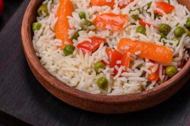 Lezzetli, sebzeli haşlanmış pirinç ya da koyu beton arka planda seramik bir tabakta tuzlu, baharatlı ve otlu risotto.