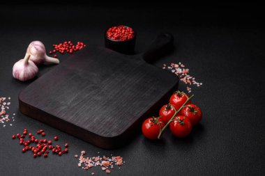 Koyu beton zeminde domates, tuz, baharat ve otlar pişirmek için gerekli malzemeler.