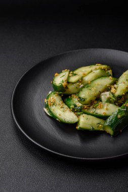 Lezzetli, sulu salatalık büyük dilimler halinde tuz, baharat ve Fransız hardalıyla koyu beton bir arka planda kesilmiş.