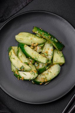 Lezzetli, sulu salatalık büyük dilimler halinde tuz, baharat ve Fransız hardalıyla koyu beton bir arka planda kesilmiş.