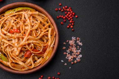 Sebzeli, mantarlı, tuzlu ve baharatlı lezzetli Asya udonu tabağı koyu beton arka planda.