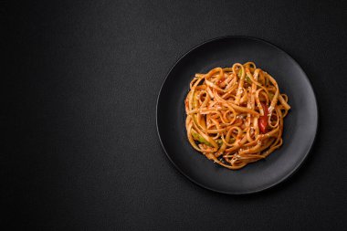 Sebzeli, mantarlı, tuzlu ve baharatlı lezzetli Asya udonu tabağı koyu beton arka planda.